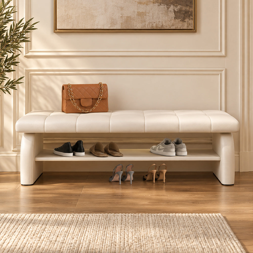 Front view of the cream upholstered shoe bench with shoes on its open lower shelf.