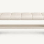 Front detail of the cream bench's stitched seat and long open shelf beneath it.