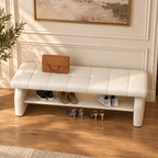 Overhead angled view of the cream bench's stitched cushion, broad side supports and shoe shelf.