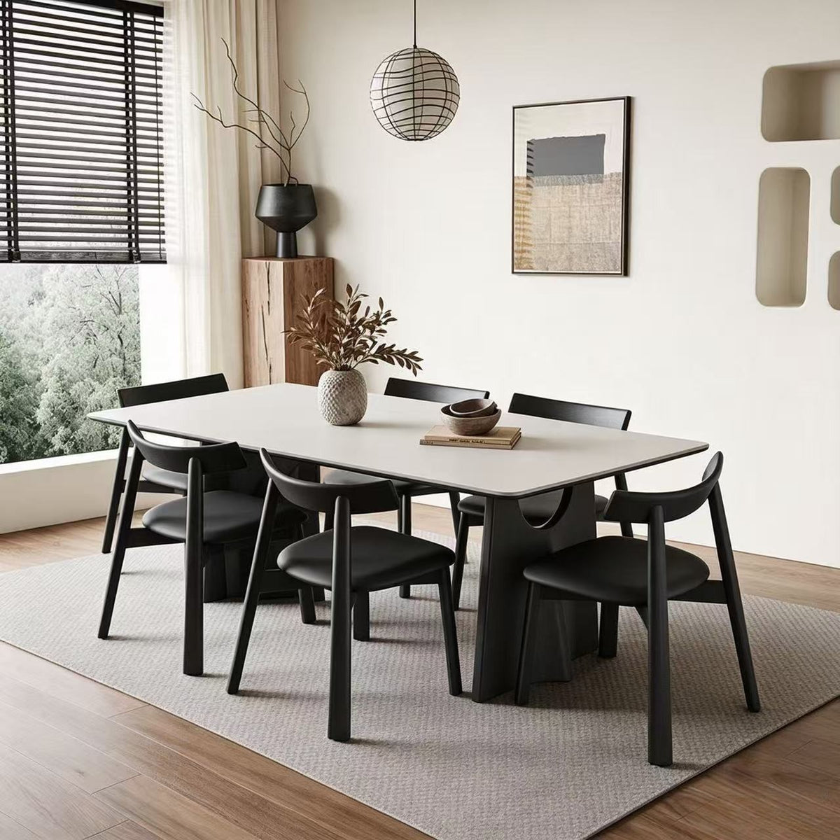 Pale rectangular dining table with black sculptural legs, surrounded by black chairs on a rug.