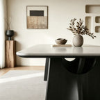 Detail of the pale dining tabletop edge above a black support with a rounded opening.