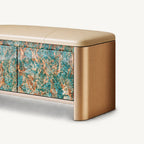 Close-up of the bench's rounded gold-tone side, beige cushion and turquoise and brown patterned door.