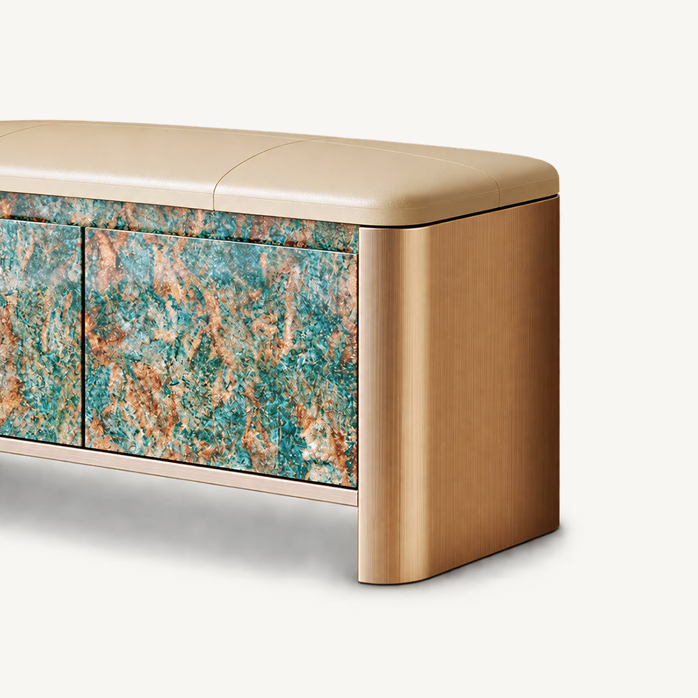Close-up of the bench's rounded gold-tone side, beige cushion and turquoise and brown patterned door.