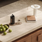 Close-up of the coffee table's pale textured rectangular top, styled with fruit, books and a vase.