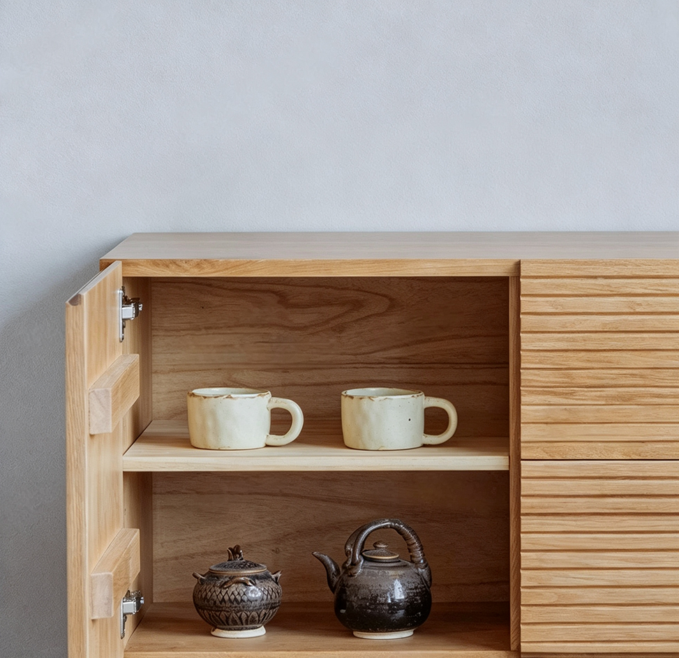Close-up of an open TV stand cupboard with shelves holding cups and teapots.