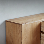 Close-up of the TV stand's light wood-grain side panel and visible corner joinery.