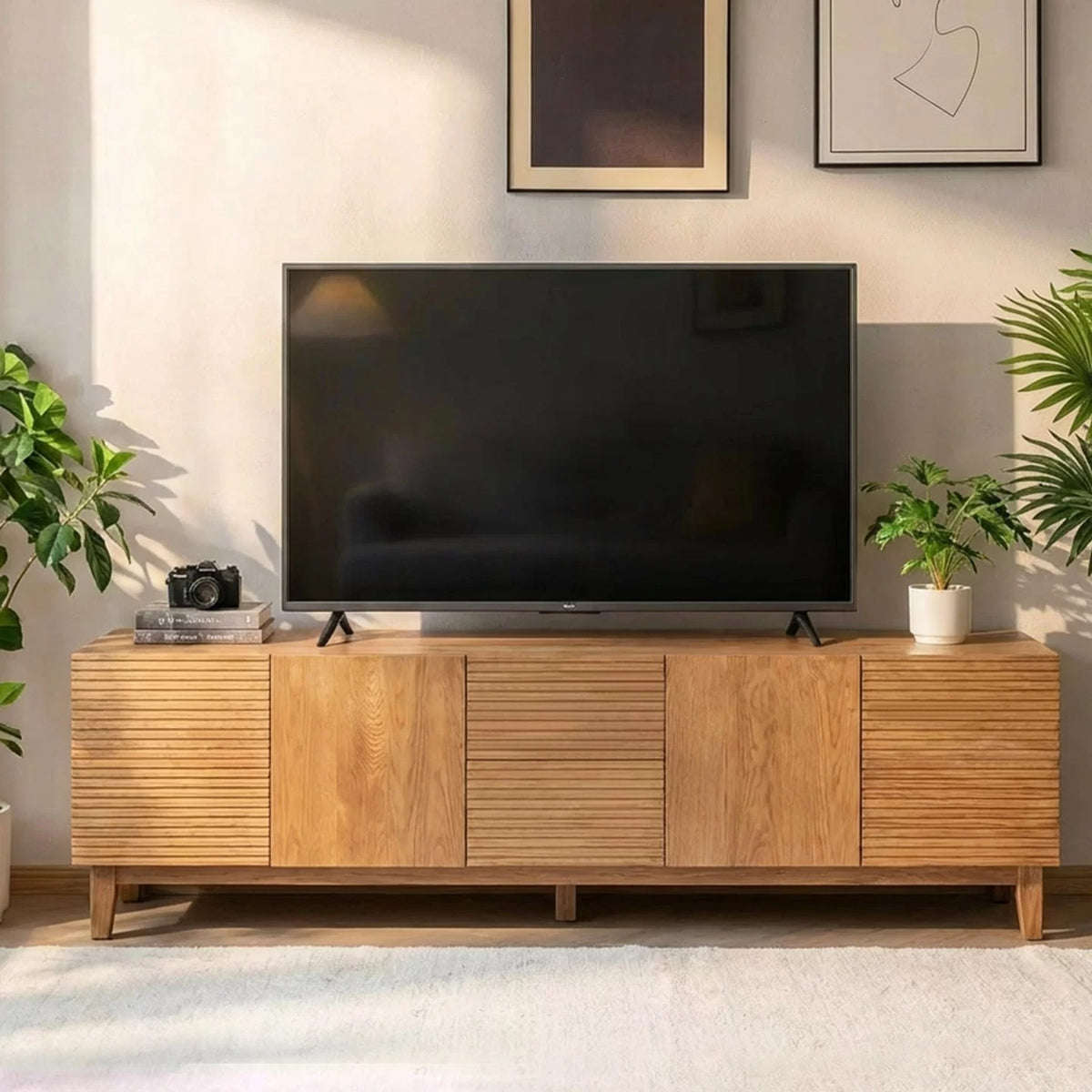 Light wood-tone TV stand with alternating smooth and horizontally ribbed fronts beneath a television.