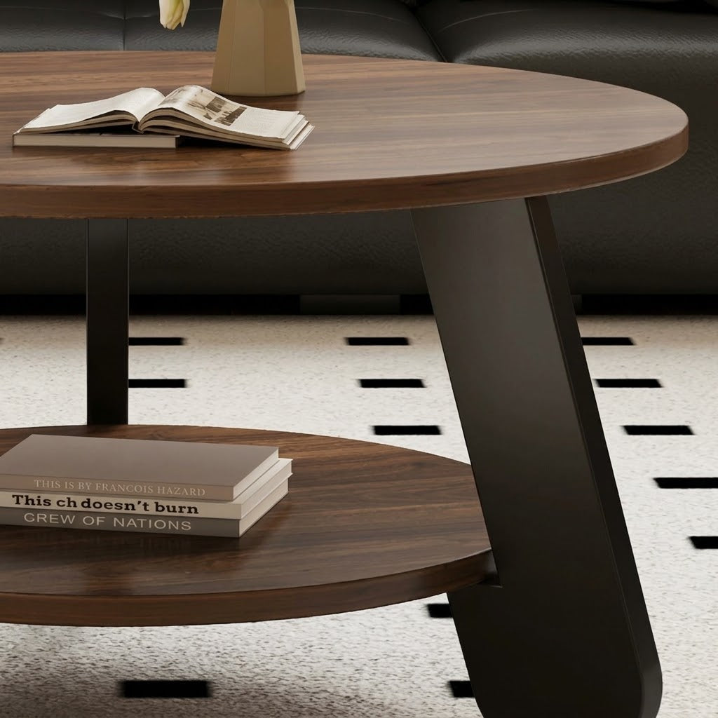 Detail of the round coffee table's brown tabletop edge, lower shelf and broad black leg.