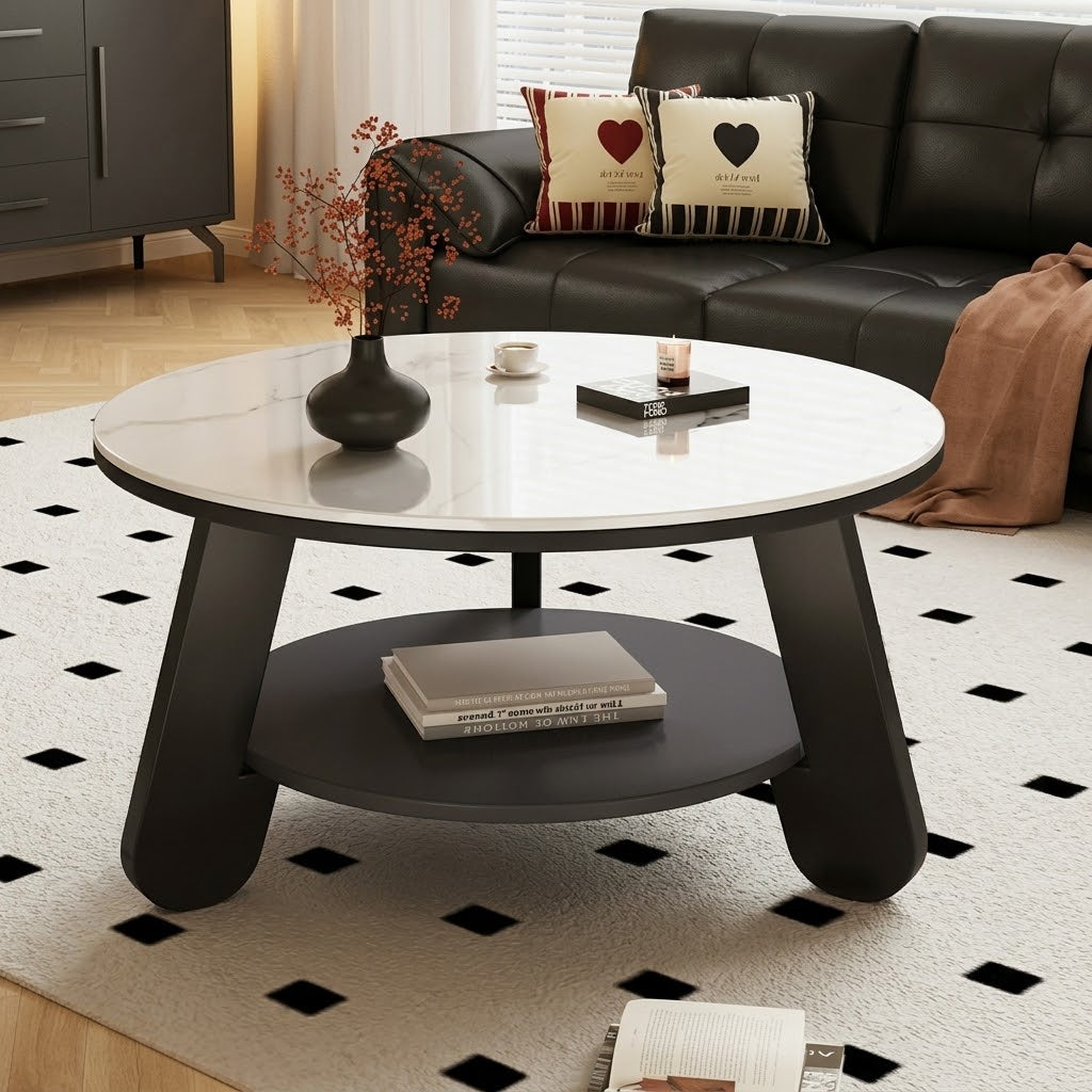 Round coffee table with a light top, dark lower shelf and angled black legs beside a black sofa.