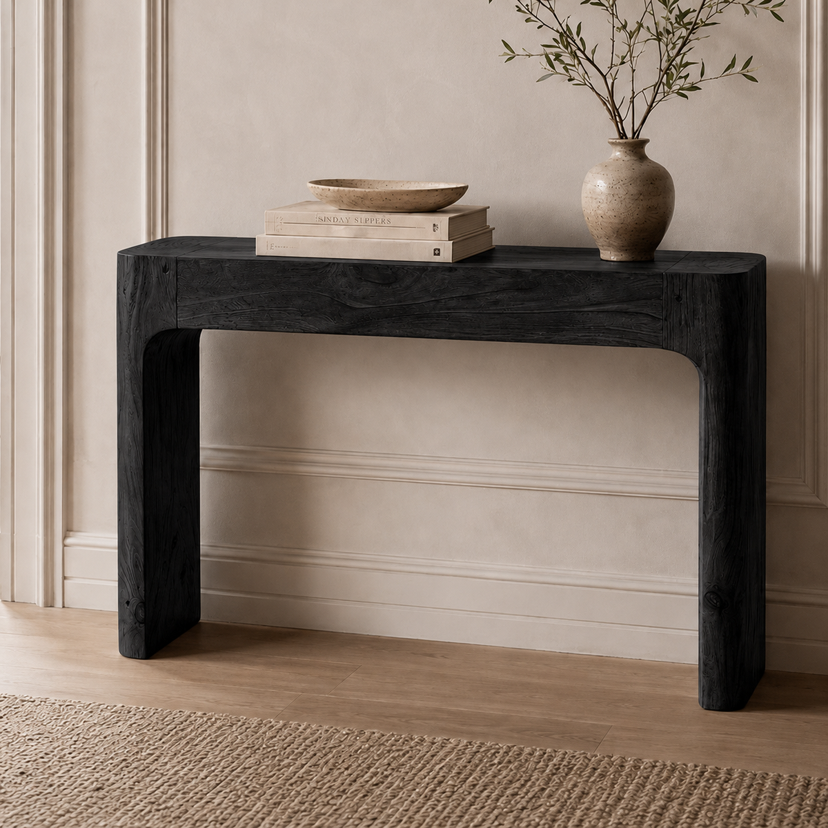 Black wood-grain console table with rounded frame corners, styled with books and a vase.