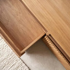Close-up of the TV stand's open drawer, wood-grain interior and ribbed front edge.