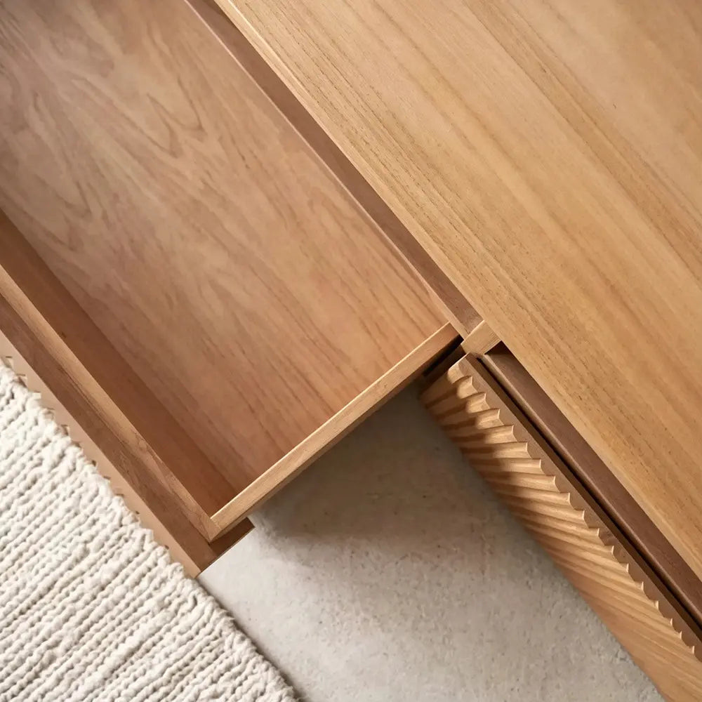 Close-up of the TV stand's open drawer, wood-grain interior and ribbed front edge.