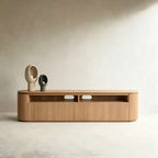 Wood-tone TV stand with rounded ends, ribbed fronts and two open media compartments, styled with sculptural vases.