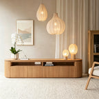 Rounded ribbed-front TV stand in a living room with pendant lights, an orchid and decorative lamps.