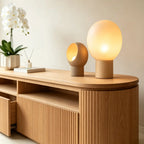 Close-up of the rounded tabletop, open media compartment and ribbed front of the wood-tone TV stand.