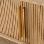 Close-up of long gold-tone handles on the TV stand's vertical slatted doors.