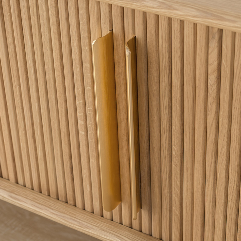 Close-up of long gold-tone handles on the TV stand's vertical slatted doors.
