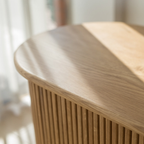 Detail of the TV stand's light wood-grain top and smoothly rounded edge.