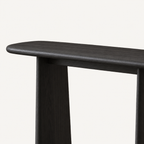 Close-up of the dark console table's rounded left tabletop edge and tapered support.