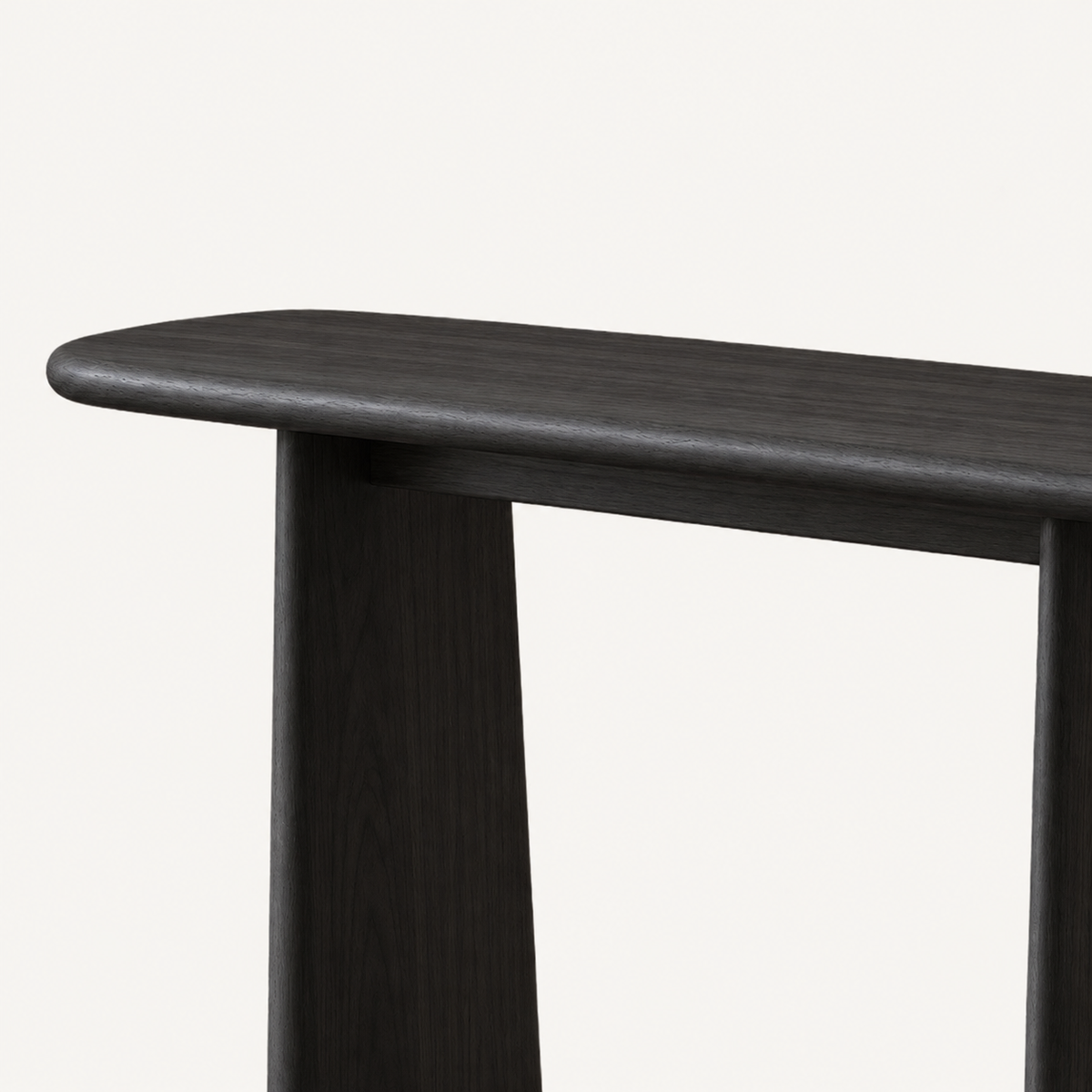 Close-up of the dark console table's rounded left tabletop edge and tapered support.