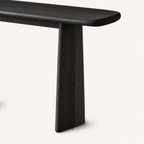 Close-up of the dark console table's right panel leg beneath its overhanging rounded top.