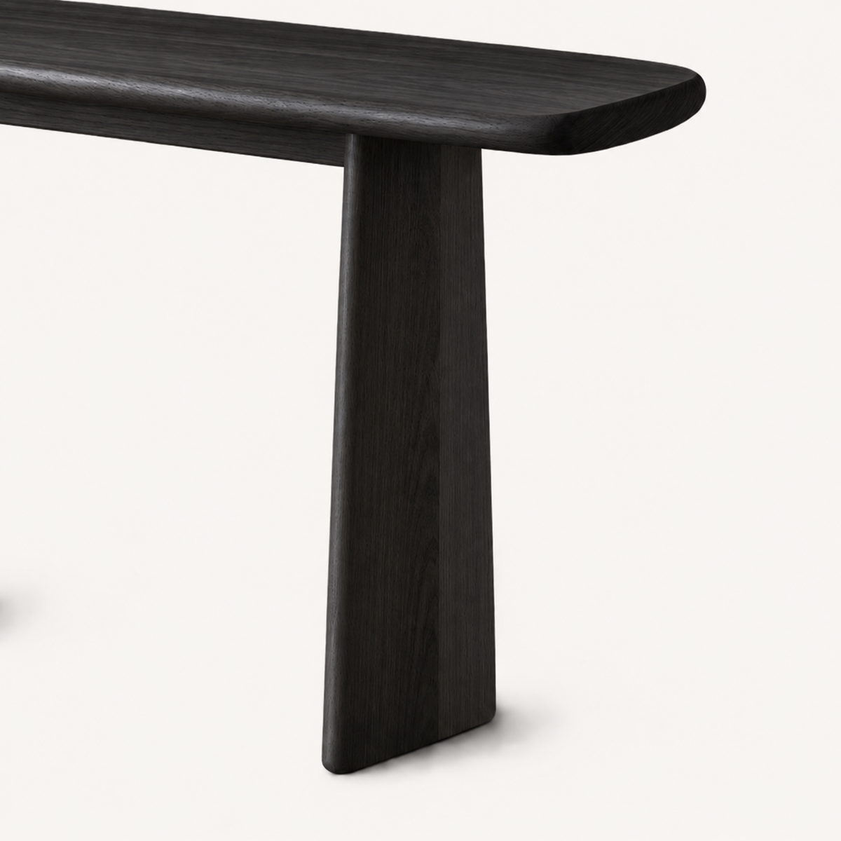 Close-up of the dark console table's right panel leg beneath its overhanging rounded top.