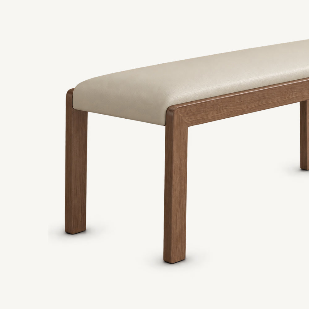 Angled detail of the cream bench seat above two slim brown legs.