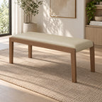 Cream upholstered bench with a brown rectangular frame and four slim legs in a bright room.