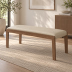 Angled room view of the cream upholstered bench with a slim wood-tone frame.