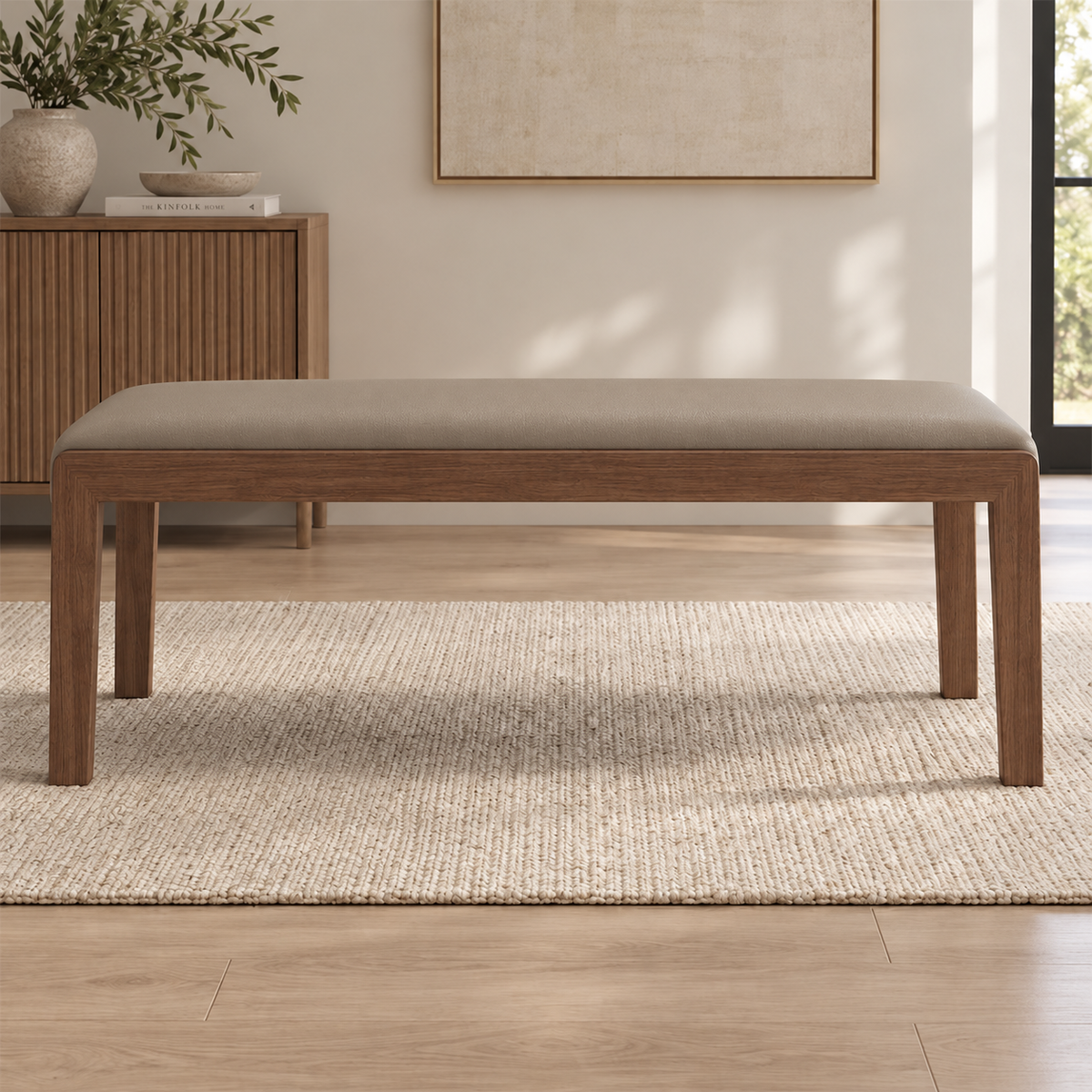Front view of the taupe padded bench seat above its brown frame and straight legs.