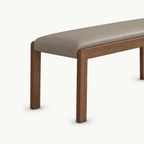 Angled detail of the taupe bench seat above two slim brown legs.