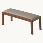 Taupe upholstered bench with a gently rounded padded seat and four slim brown legs.
