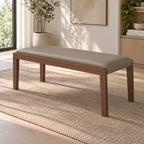 Taupe upholstered bench on a woven rug, showing its brown frame and slim straight legs.
