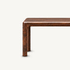 Close-up of the brown bench's rounded seat-to-leg corner and slim front leg.
