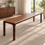 Angled side view of the long brown bench with slender rounded legs in a bright room.