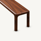 Overhead detail of the bench's brown wood-grain seat, rounded end and pair of slim legs.