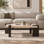 Front room view of the square coffee table with a light speckled top and broad dark brown legs.