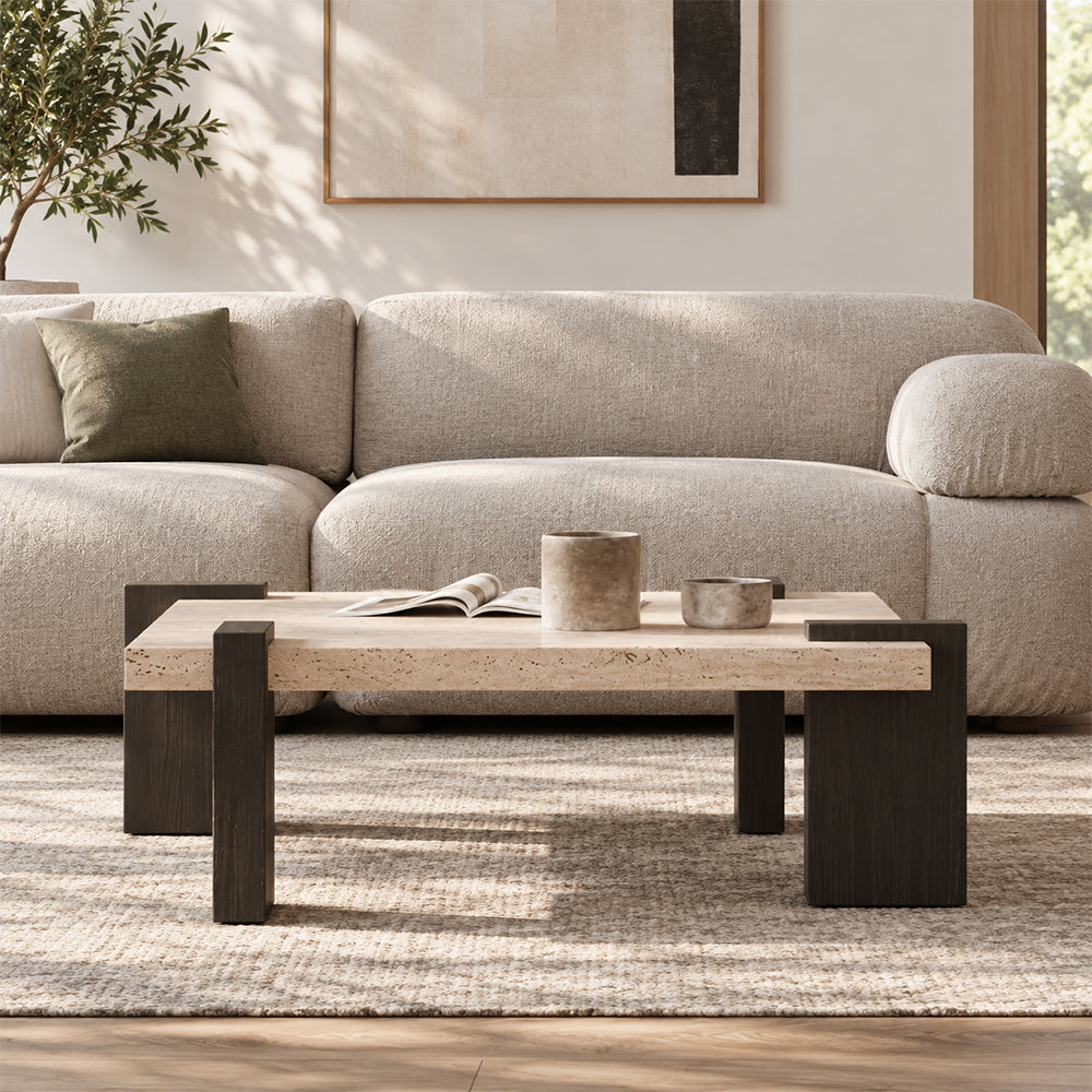 Front room view of the square coffee table with a light speckled top and broad dark brown legs.