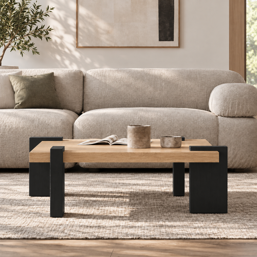 Front room view of the square coffee table with a light wood-grain top and broad black legs.