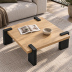 Square coffee table with a light wood-grain top and black block legs extending over its edges, viewed from above.