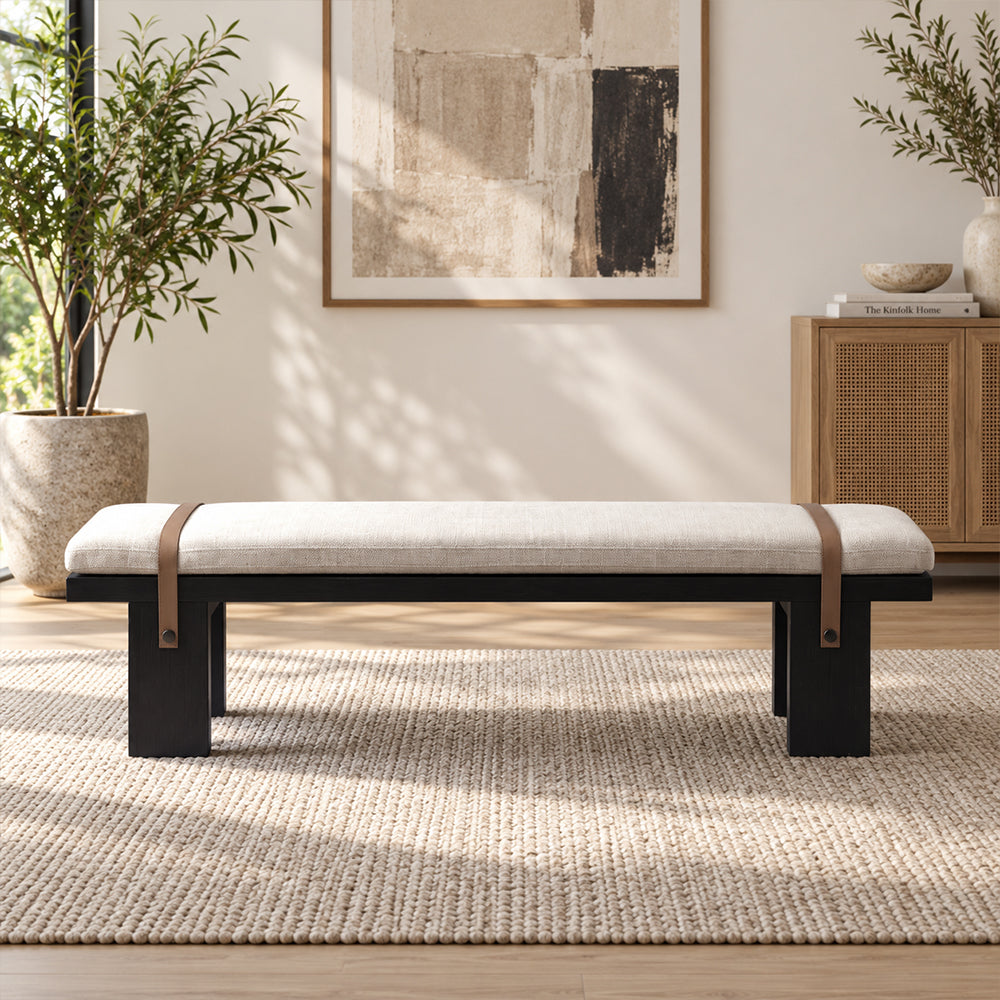 Front view of the cream-cushioned black bench with two brown decorative straps.