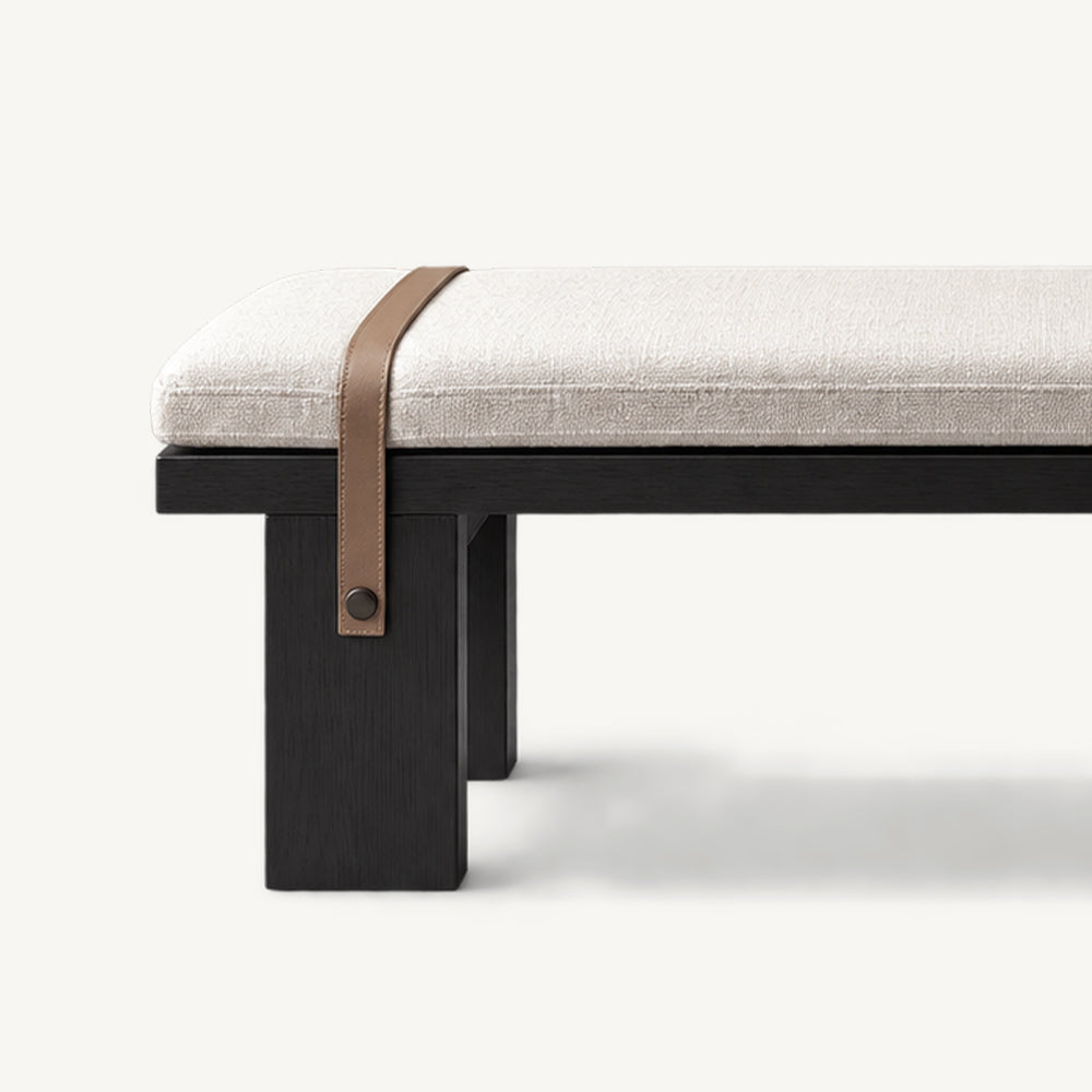 Close-up of a brown strap crossing the cream bench cushion and fastening to a black leg.