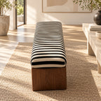 End view of the striped upholstered bench showing its rounded cushion and brown panel support.