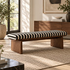 Black-and-cream striped bench with a brown wood-tone frame on a pale woven rug.