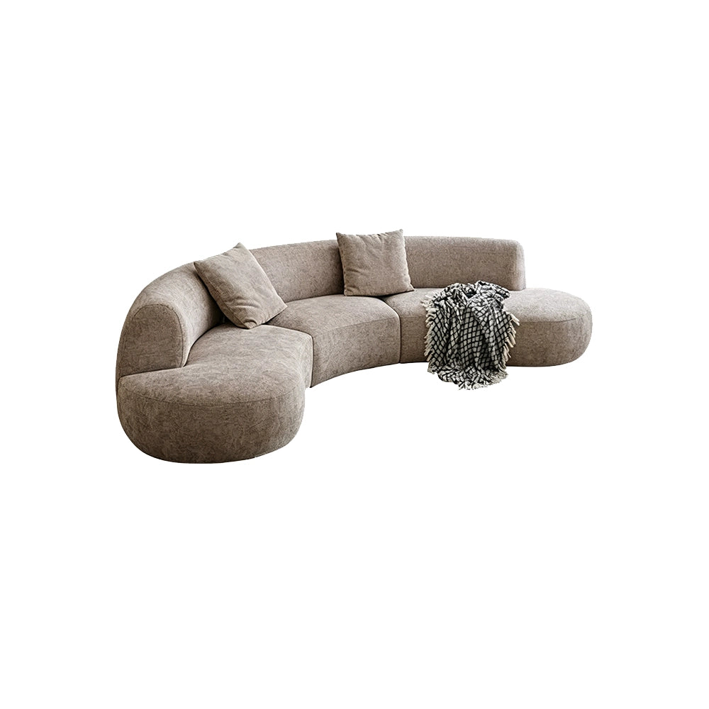 Taupe curved modular sofa with rounded end seats and loose cushions on a white background.