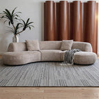 Taupe curved modular sofa with rounded end seats, loose cushions and a patterned throw.