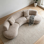 Overhead angled view of the taupe crescent-shaped sofa and its rounded seat modules.