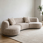 Angled view of the taupe modular sofa with a curved back and rounded end seats.