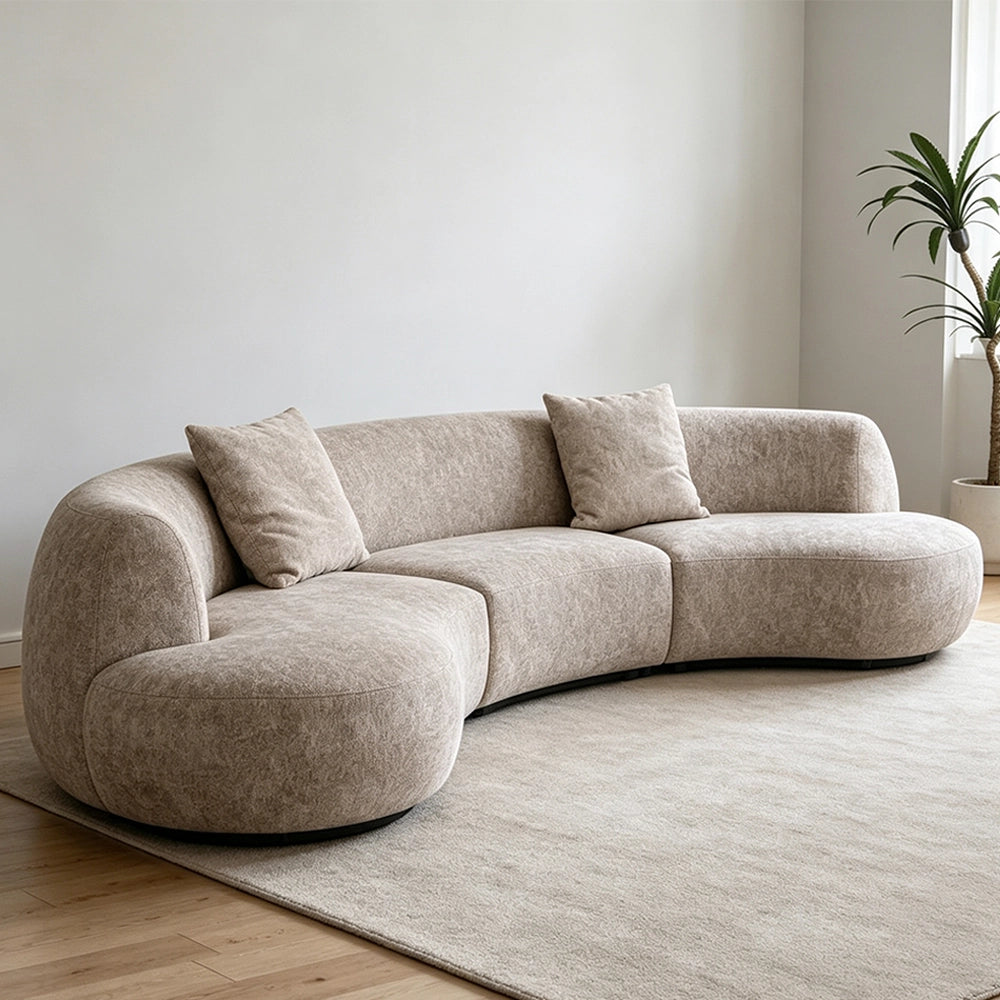 Angled view of the taupe modular sofa with a curved back and rounded end seats.