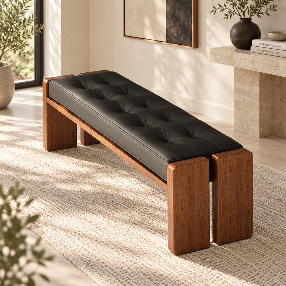 Overhead angled view of the black button-tufted bench seat and split brown end legs.